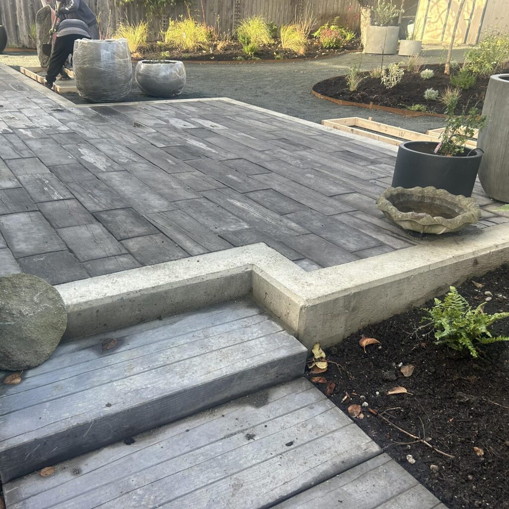 Paved garden area with planters, featuring paving planks and pony wall by CBS Masonry.